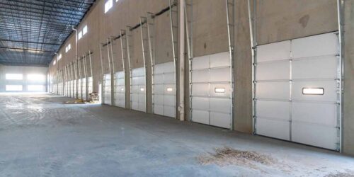 Overhead Garage Doors lining an empty warehouse.