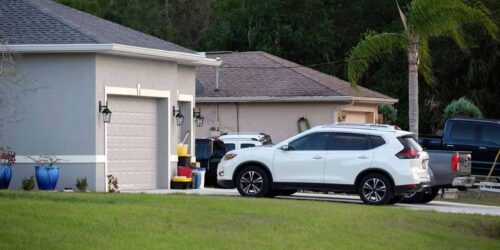 Car parked in front of wide garage double door on concrete driveway of new modern american house.