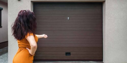 Garage door PVC. Girl or young woman holds remote controller fo