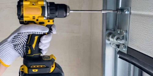 A craftsman assembles sectional doors using a screwdriver. The concept of sectional door installation.