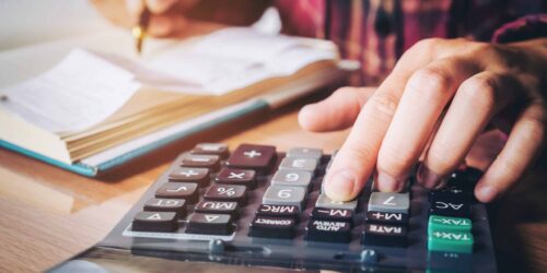 Businessman's hands with calculator and cost at the office and Financial data analyzing counting on wood desk